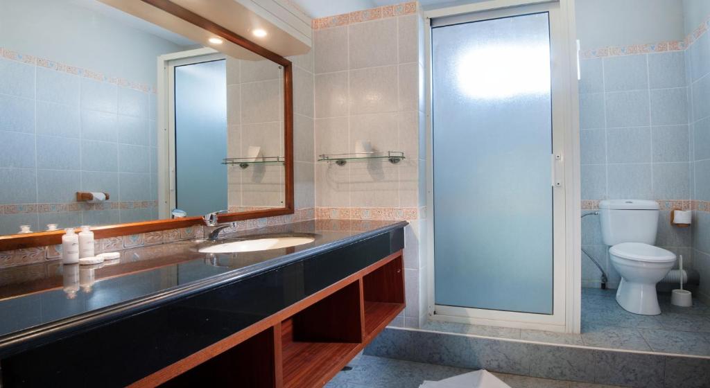 Mūsdienīgs vannas istabas interjers ar melnu akmens izlietni, spoguli un dušas kabīni, kā arī tualeti. Elegants dizains un gaišas krāsas rada patīkamu atmosfēru.