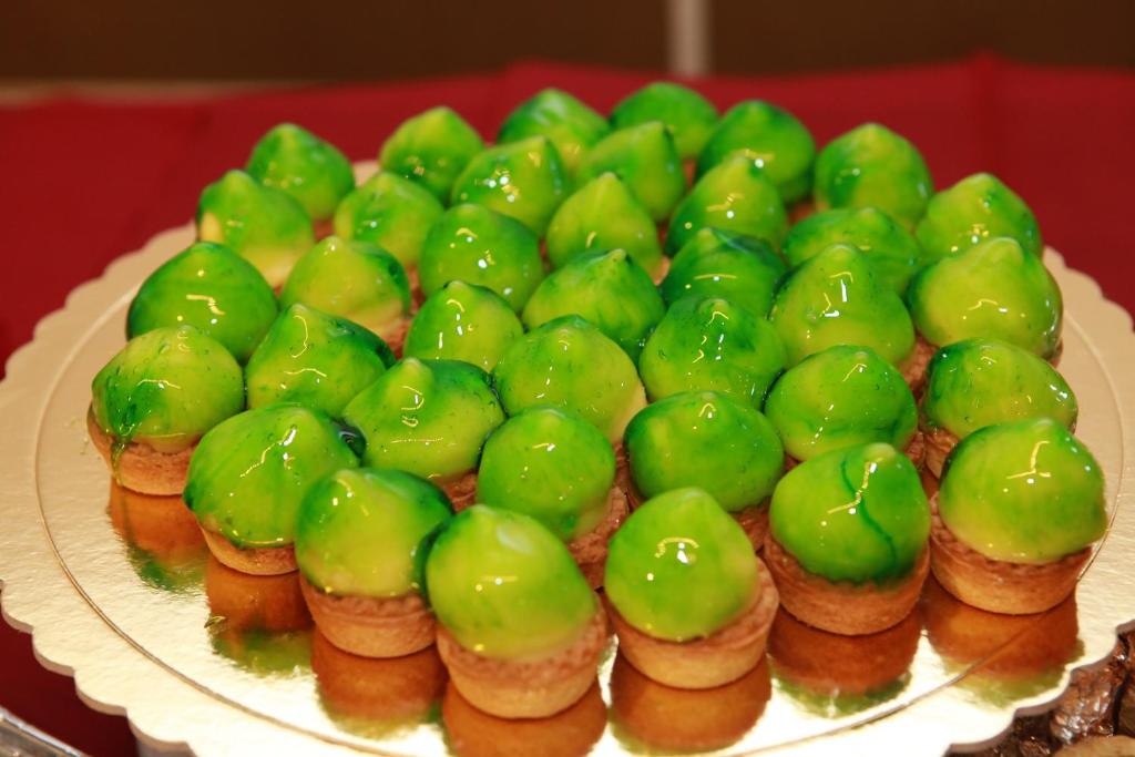 Zaļās konfektes ar spīdīgu glazūru uz kārtainās mīklas pamatnes, sakārtotas dekoratīvā formā. Ideāla izvēle desertu mīļotājiem.