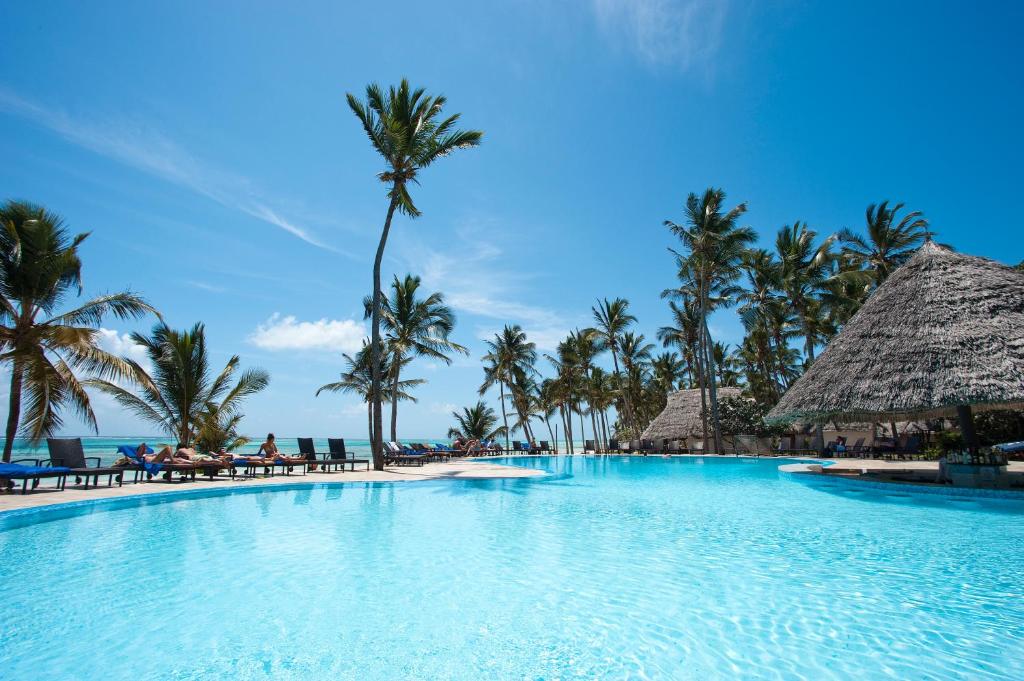 Tropu baseins ar palmām un saulainu debesi, ideāls atpūtai pie jūras. Relaksējoša atmosfēra un brīnišķīgs skats uz okeānu.