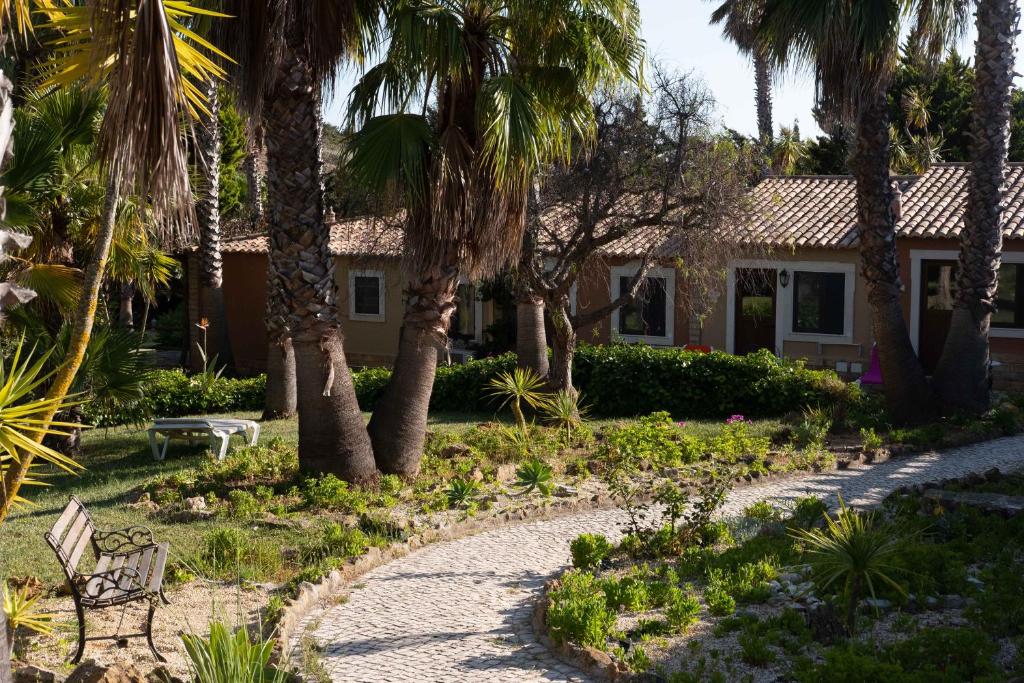 Dārza ainava ar palmu kokiem un viesnīcas numuriem pie Quinta do Mar Country & Sea Village