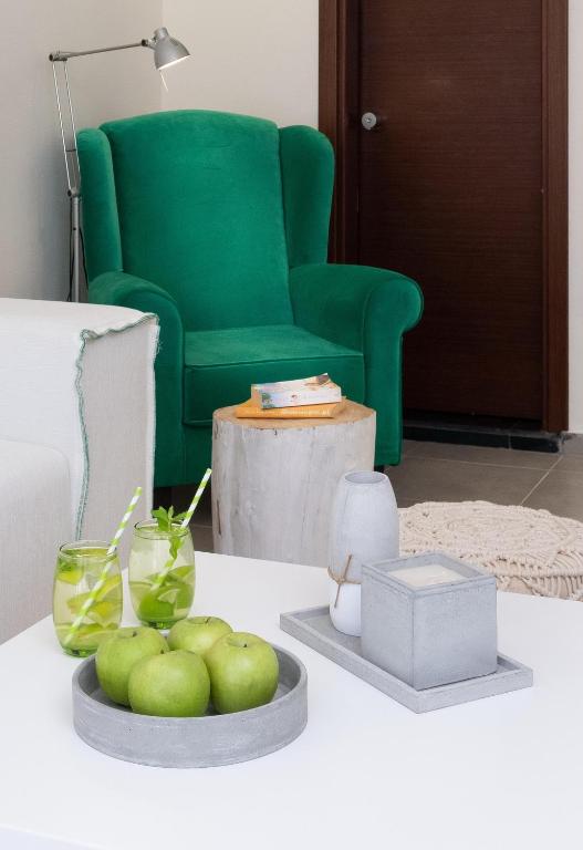 Mūsdienīgs viesnīcas numurs ar zaļo krēslu un svaigiem āboliem, Eva Mare Hotel & Suites.