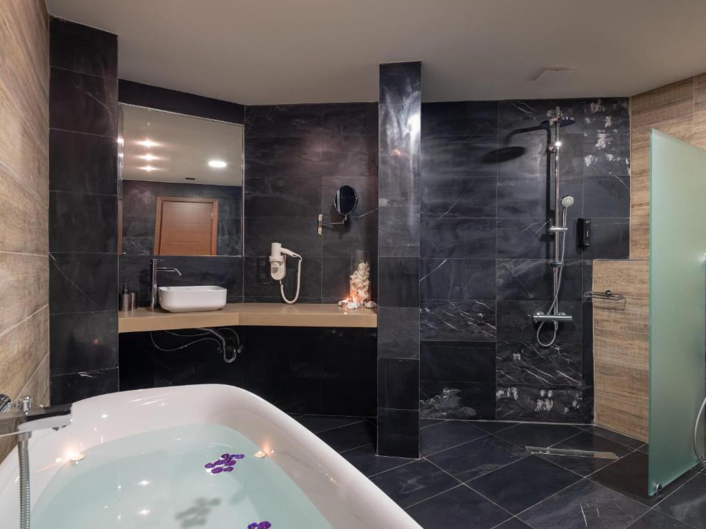 Mūsdienīgs vannas istabas interjers Eva Mare Hotel & Suites ar elegantu vannu un dušu.