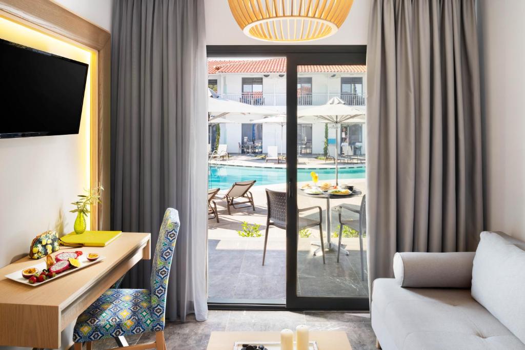 Mūsdienīga viesnīcas numura interjers ar skatu uz baseinu. Gaišas krāsas aizkari un stilīgs mēbeļu dizains, kas rada relaksējošu atmosfēru.