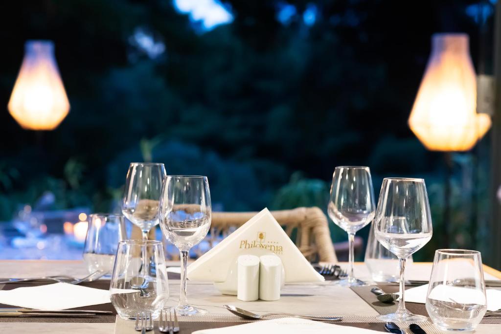 Elegantā galda uzstādīšana ar glāzēm un izvēlni, kas radīta romantiskai vakariņu atmosfērai, apgaismota ar mīkstu gaismu.