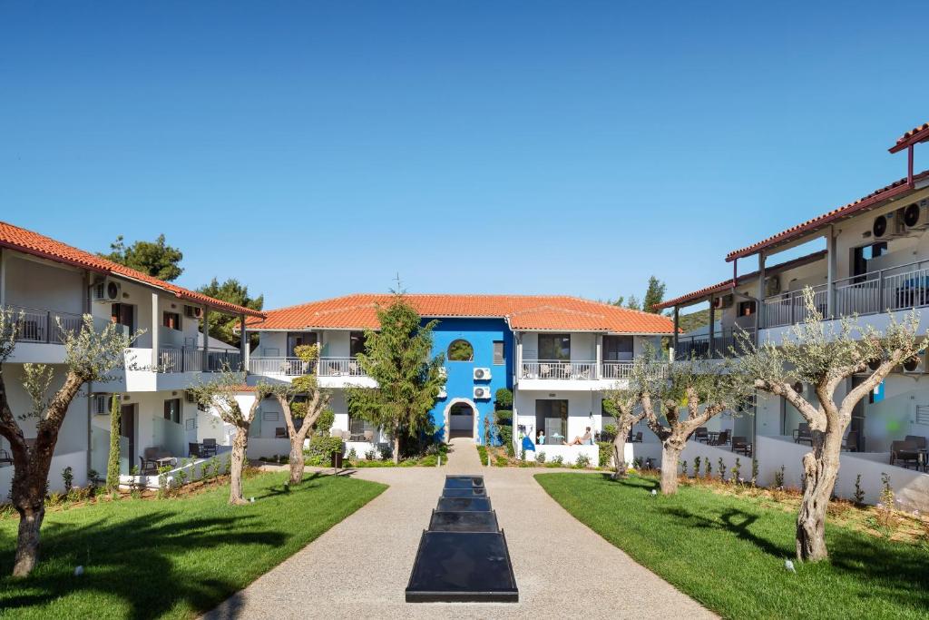 Mūsdienīga viesnīca ar baltiem un sarkaniem jumtiem, apzaļumota teritorija un centrāla ieeja ar zilu fasādi. Vides dizains apvieno dabu un komfortu, radot relaksējošu atmosfēru.