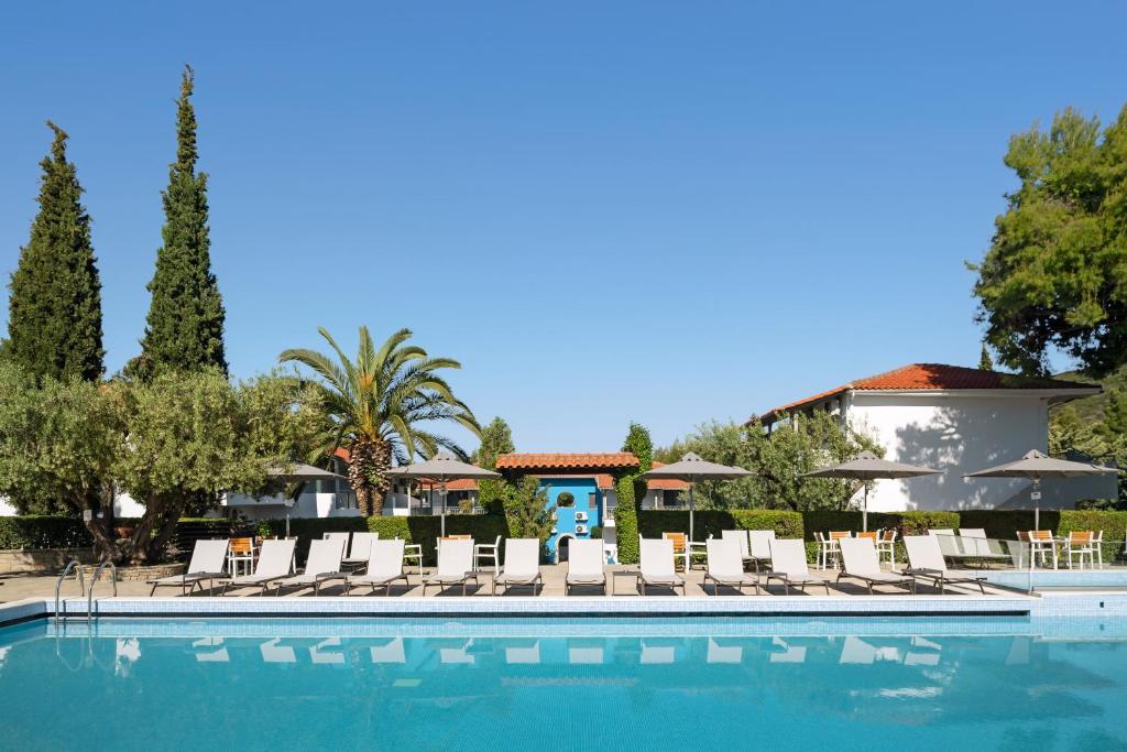 Baseins ar sauļošanās krēsliem un palmām, apzaļumota teritorija un skaidrs debesis. Ideāla vieta atpūtai un relaksācijai.