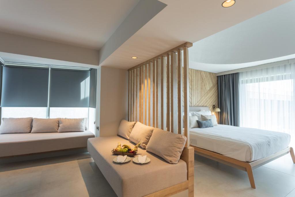 Mūsdienīgs numurs viesnīcā Paloma Orenda ar ērtu dīvānu un gultu.