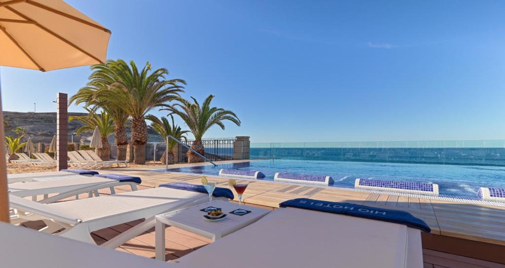 Lieliska atpūtas zona ar baseinu, palmām un skatu uz jūru, kas rada relaksējošu atmosfēru. Ideāla vieta, lai izbaudītu sauli un dzērienus.