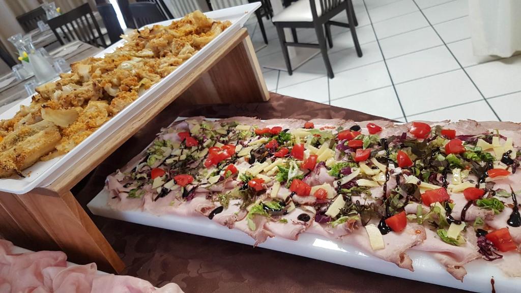 Uz galda atrodas divi dažādi ēdieni: augšējā daļā ir cepti dārzeņi ar kraukšķīgu garoziņu, bet apakšējā daļā ir šķēlēs sagriezta gaļa ar svaigiem dārzeņiem un mērci.