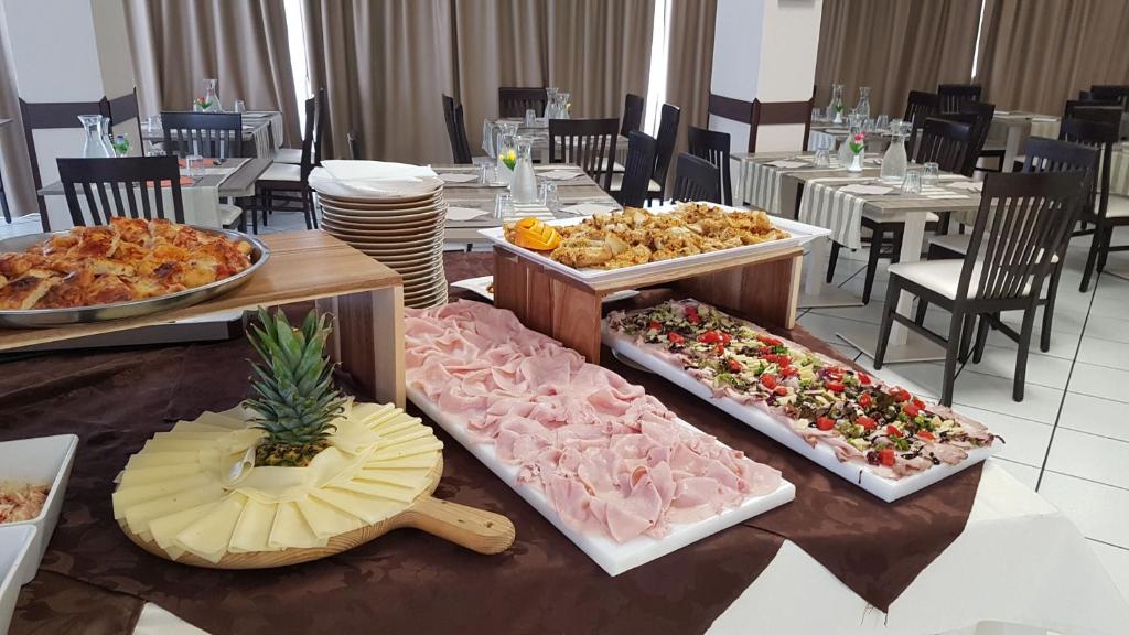 Bufete ar dažādām gaļas, siera un dārzeņu uzkodām, kas sakārtotas uz galda, papildināts ar ananāsu un salātiem. Restorāna interjers ar galds un krēsli aicina uz pasākumu.