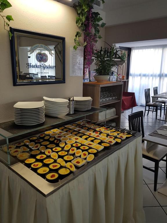 Deserts un saldumi izkārtojums restorānā ar dažādiem krēmveidīgiem ēdieniem, ko rotā ogas. Fons ietver galdu un krēslus, kā arī dekoratīvas detaļas.