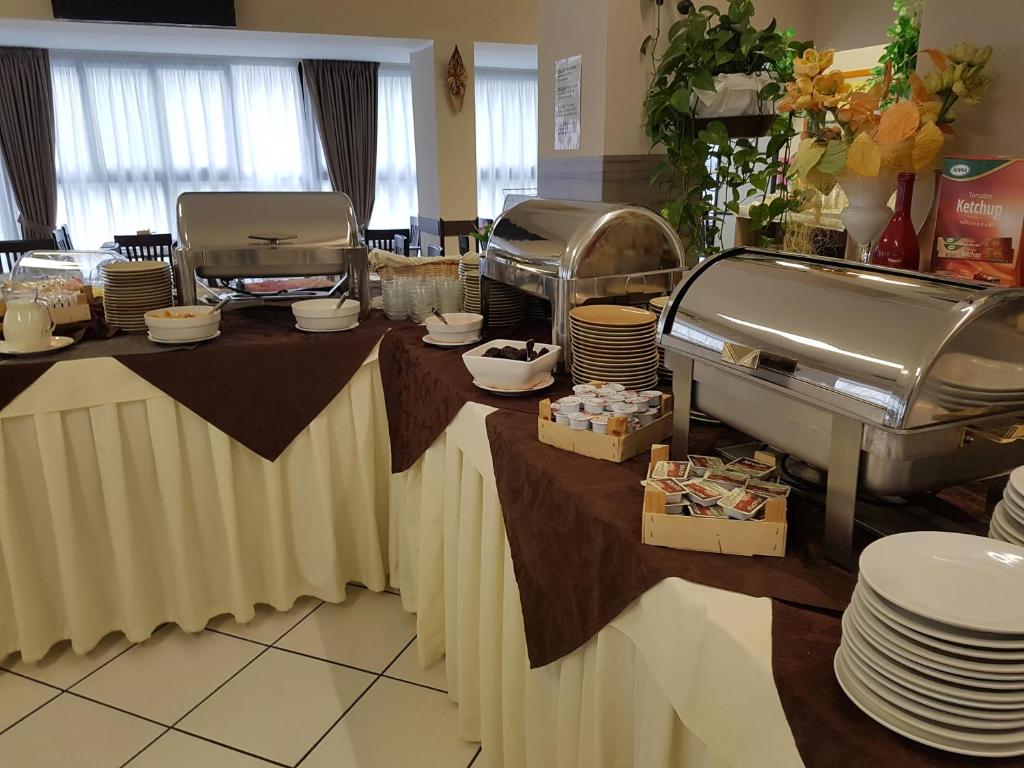 Bufete ar dažādiem traukiem un ēdieniem, kas pasniegti uz galdiem ar brūnu galdautu. Galdi ir dekorēti ar ziediem un salvetēm, radot viesmīlīgu atmosfēru.