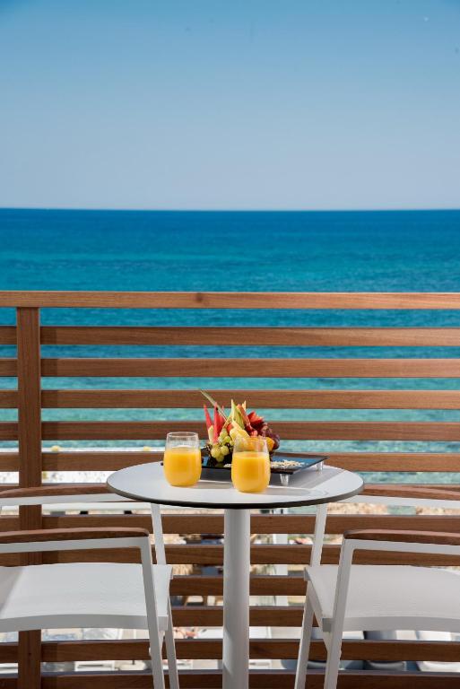 Skats no Enorme Ammos Beach Resort balkona uz jūru ar augļu šķīvi un dzērieniem.