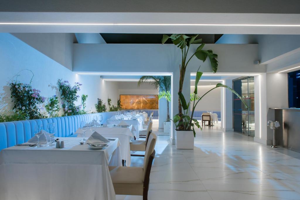 Mūsdienīgs restorāns I-Resort Beach Hotel & Spa ar elegantiem galdiem un zaļumiem.