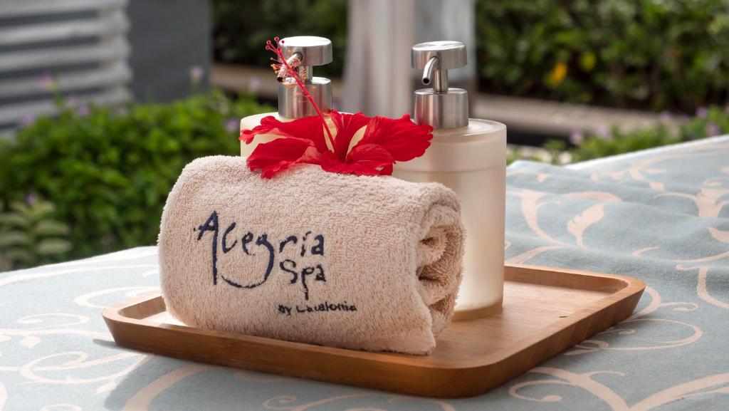 Skaists spa komplekts ar mīkstu dvieli, ziedu un kosmētikas pudelēm, kas sakārtotas uz koka paletes. Ideāla aina relaksācijai un labsajūtai.