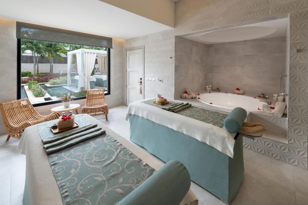 Mūsdienīgs spa telpa ar divām masāžas galdiem, relaksējošu atmosfēru un skatu uz dārzu. Telpā atrodas arī grezna vanna ar ziedlapiņām un ērtas sēdvietas.