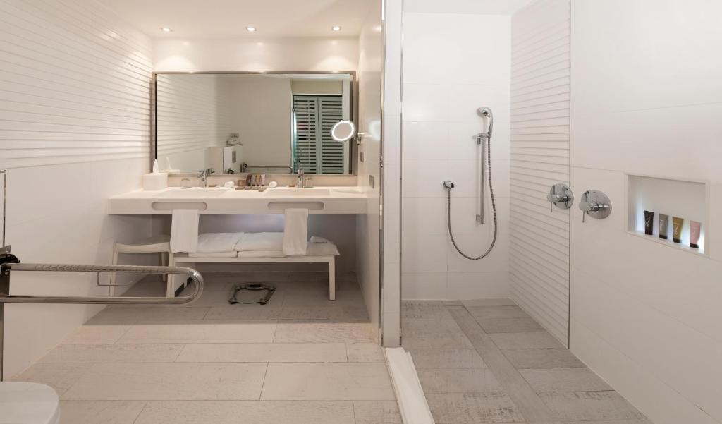 Mūsdienīgs vannas istabas interjers ar diviem izlietnēm, lielu spoguli un dušas zonu. Gaišas krāsas un eleganta dizaina elementi rada relaksējošu atmosfēru.