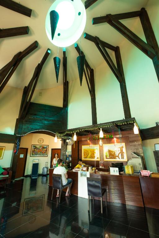 Mūsdienīga viesnīcas recepcija ar augstu, koka konstrukcijas griestu dizainu un mūsdienīgu apgaismojumu, kur viesi tiek apkalpoti.