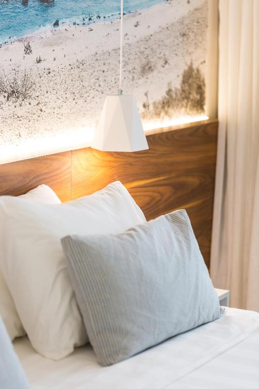 Moderna gultas daļa ar spilveniem un piekārto lampu Atrium Ambiance Hotel