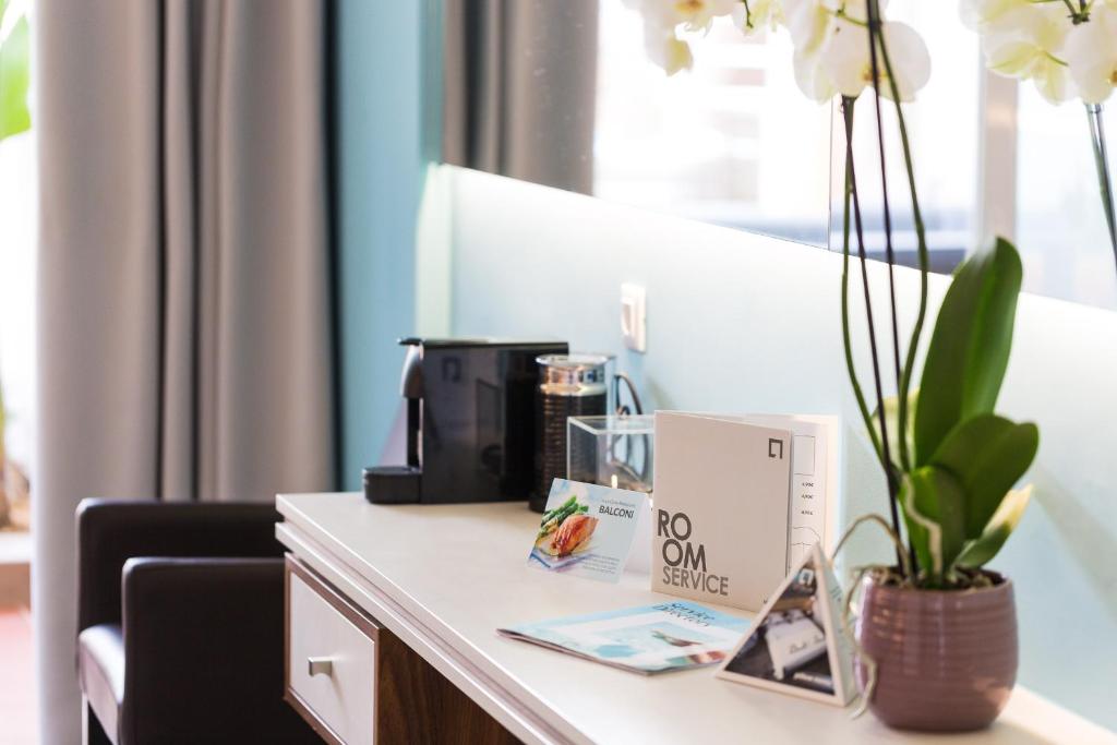 Atrium Ambiance Hotel numura galda izvietojums ar kafijas aparātu un orhidejām.