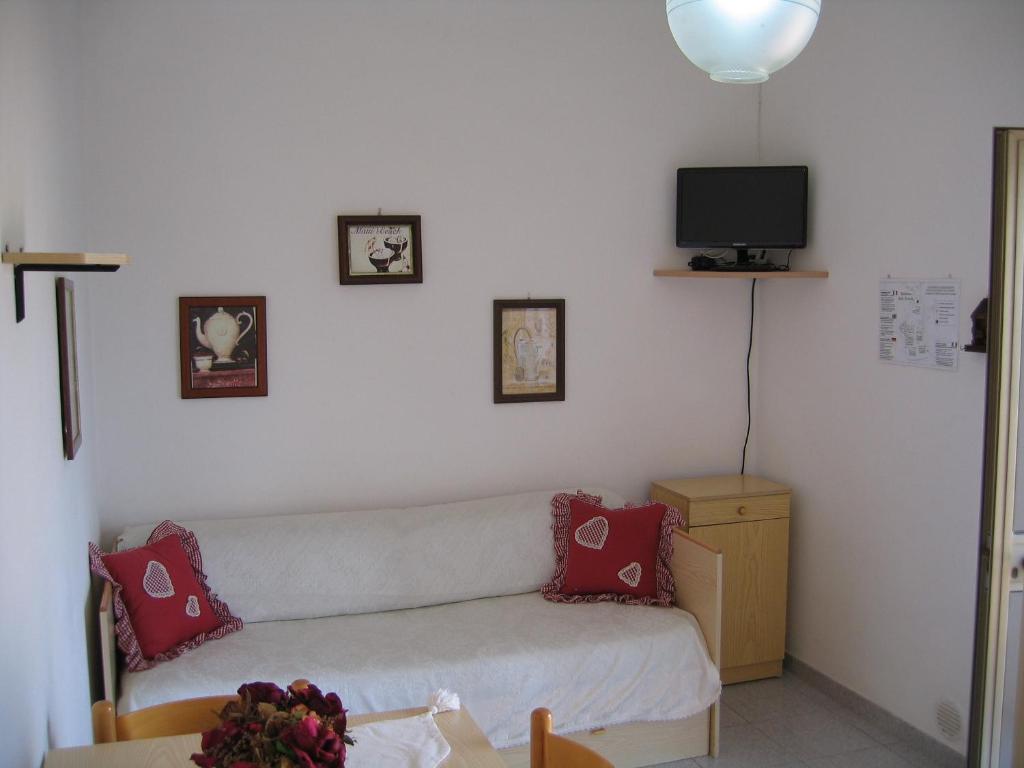 Mājīgs dzīvojamās istabas interjers ar dīvānu, televizoru un dekoratīvām gleznām uz sienām. Telpā ir gaiša apgaismojuma un koka mēbeles, radot patīkamu atmosfēru.