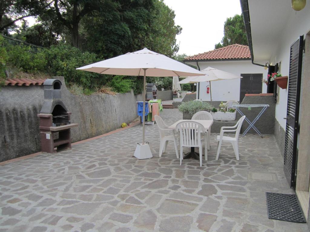 Āra terase ar akmens grīdu, galdu un krēsliem, saulessargiem un grilu, kas veido patīkamu atpūtas vietu. Apkārt augi un mājas fons piešķir viesmīlīgu atmosfēru.