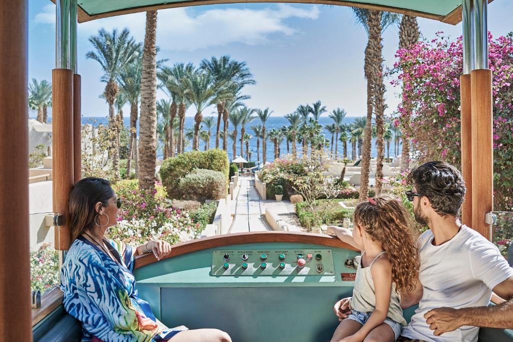 Ģimene brauc ar funikulieri Four Seasons Resort Sharm El Sheikh, vērojot palmas un jūru.