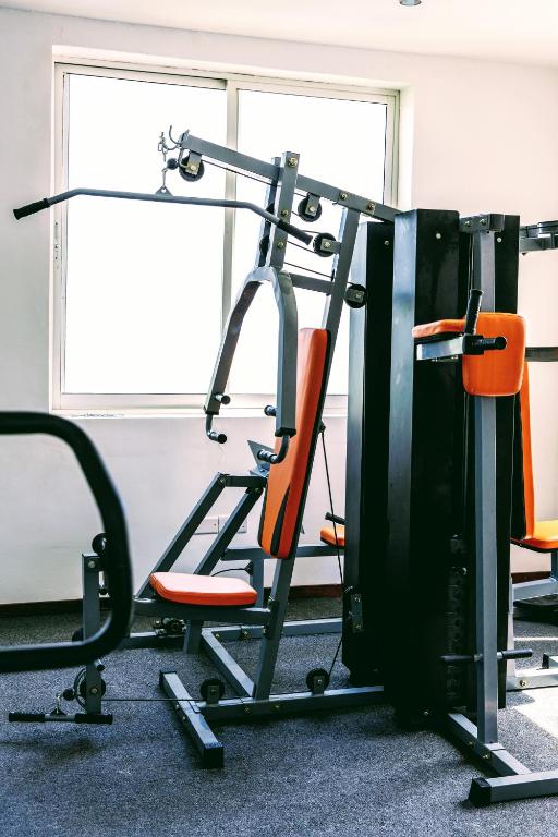 Sporta zāles aprīkojums ar oranžām sēdvietām un logu, kas nodrošina dabīgu apgaismojumu.