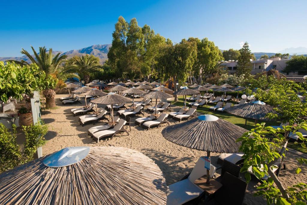 Pludmales zona ar sauļošanās krēsliem un salmiem, apzaļumots fons un kalnu ainava. Ideāla vieta relaksācijai un atpūtai saulainā dienā.