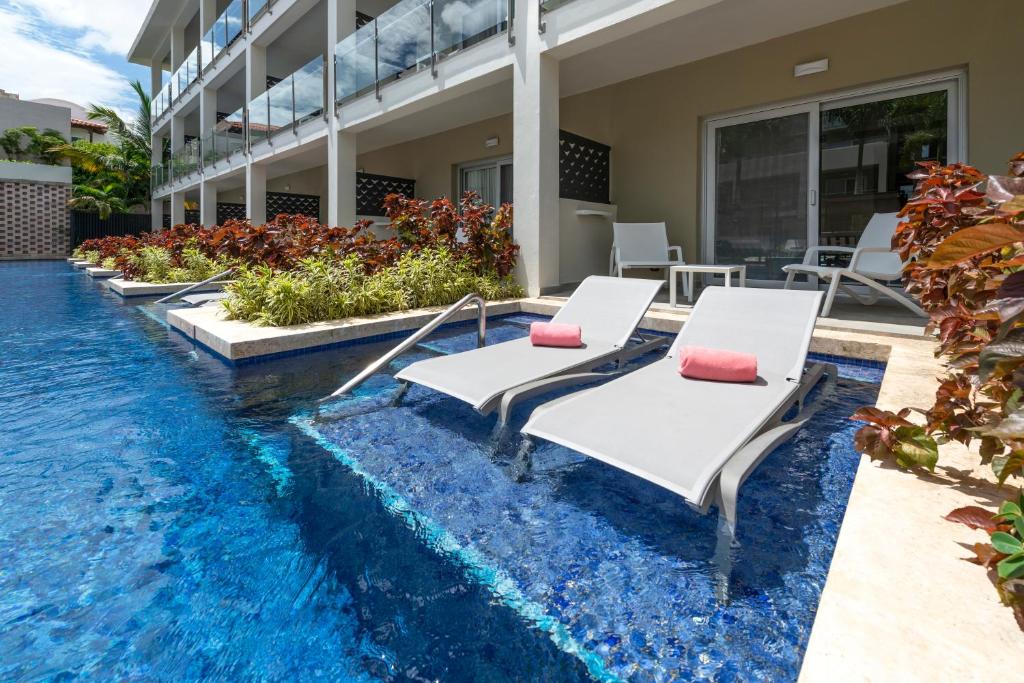 Atpūtas zona ar sauļošanās krēsliem blakus peldbaseinam, ko ieskauj sulīgas augu kompozīcijas. Ideāla vieta relaksācijai un brīvdienu baudīšanai.