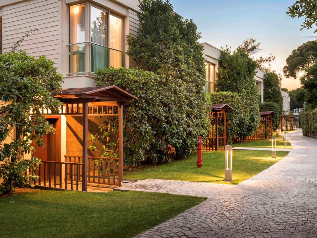 Rixos Premium Belek numuru ārpuse ar skaistu dārzu un apgaismojumu.