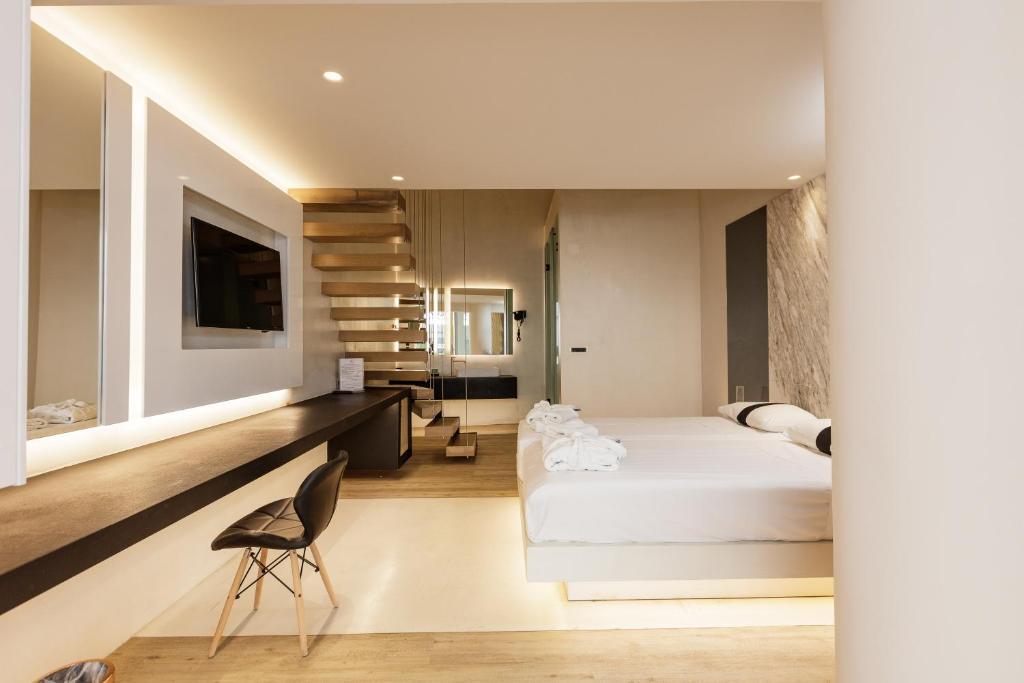 Mūsdienīga guļamistaba ar koka grīdu, vieglām krāsām un stilīgu interjeru, kurā ietilpst gulta, televizors un kāpnes. Guļamistaba ir aprīkota ar ērtu darba staciju un pievilcīgu apgaismojumu.