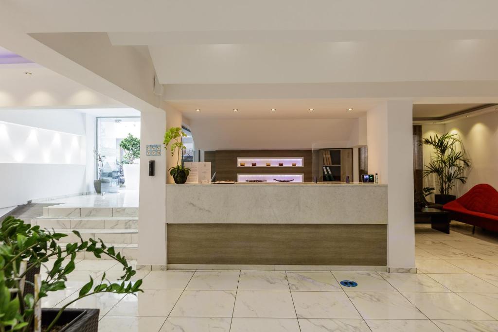 Mūsdienīga viesnīcas reģistratūra ar elegantām interjera detaļām, tostarp augu un sarkanām mēbelēm. Gaisma un telpas plūsma rada viesmīlīgu atmosfēru.
