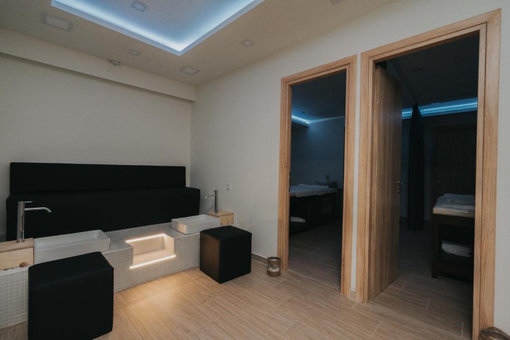 Mūsdienīgs spa interjers ar melnu dīvānu un divām durvīm, kas ved uz atsevišķām telpām. Telpa ir apgaismota ar zilu gaismu un satur elegantu, minimālistisku dizainu.