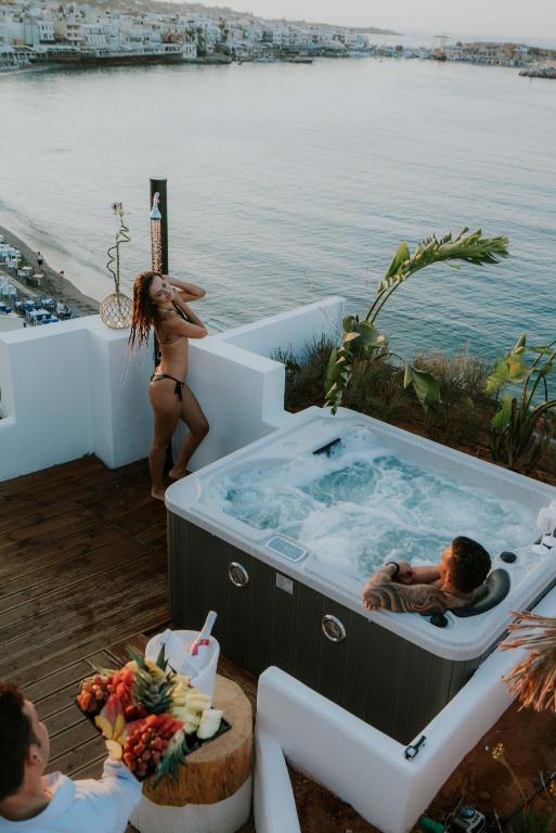 Relaksējoša brīvdienu aina ar džakuzi, kas atrodas pie ūdens, un cilvēkiem, kas bauda sauli un dabu. Fons veido skaista jūras ainava un krāšņas pilsētas mājas.