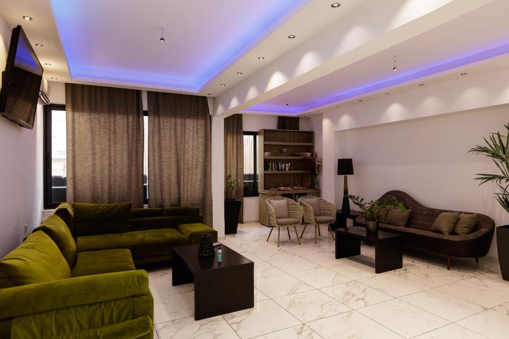 Mūsdienīgs viesistabas interjers ar zaļiem dīvāniem, melnu kafijas galdiņu un atpūtas krēsliem. Telpā ir gaiša apgaismojuma sistēma un eleganta dekorācija.