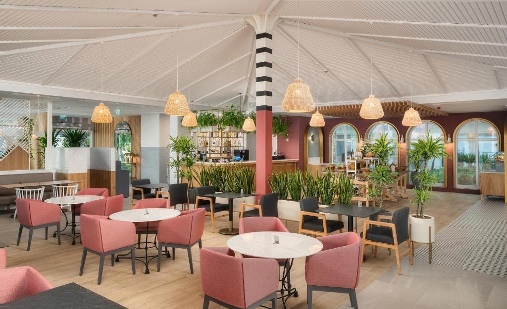 Mūsdienīgs restorāns Corendon Playa Kemer ar augu rotājumiem un komfortablām mēbelēm.