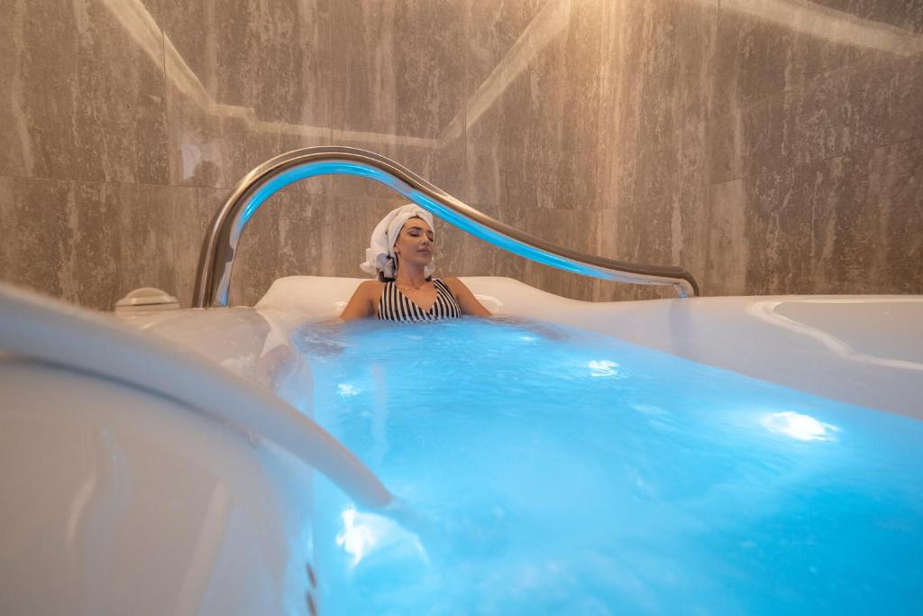 Relaksējoša brīvdiena spa, kur sieviete bauda vannu ar zilu apgaismojumu. Ideāla atmosfēra atpūtai un labsajūtai.