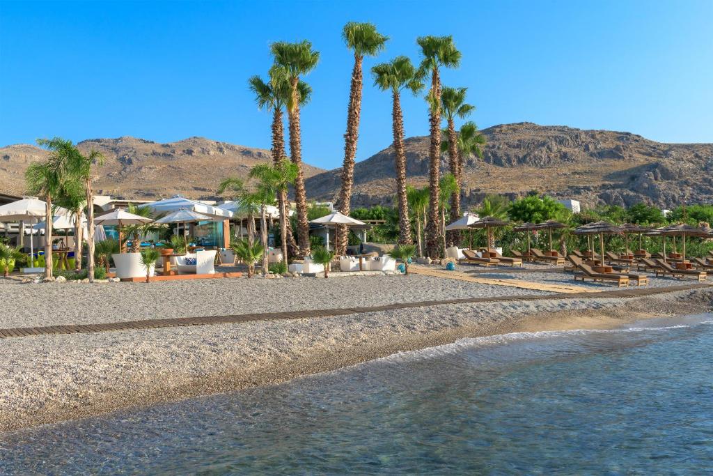 Aquagrand Exclusive Deluxe Resort piekrastē ar palmām un sauļošanās krēsliem