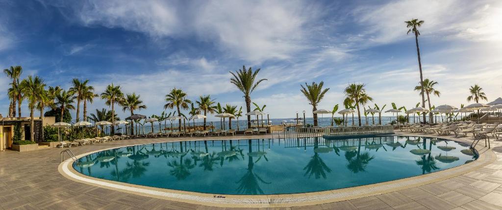 Aria Resort & Spa Hotel baseins ar palmām un skatu uz jūru