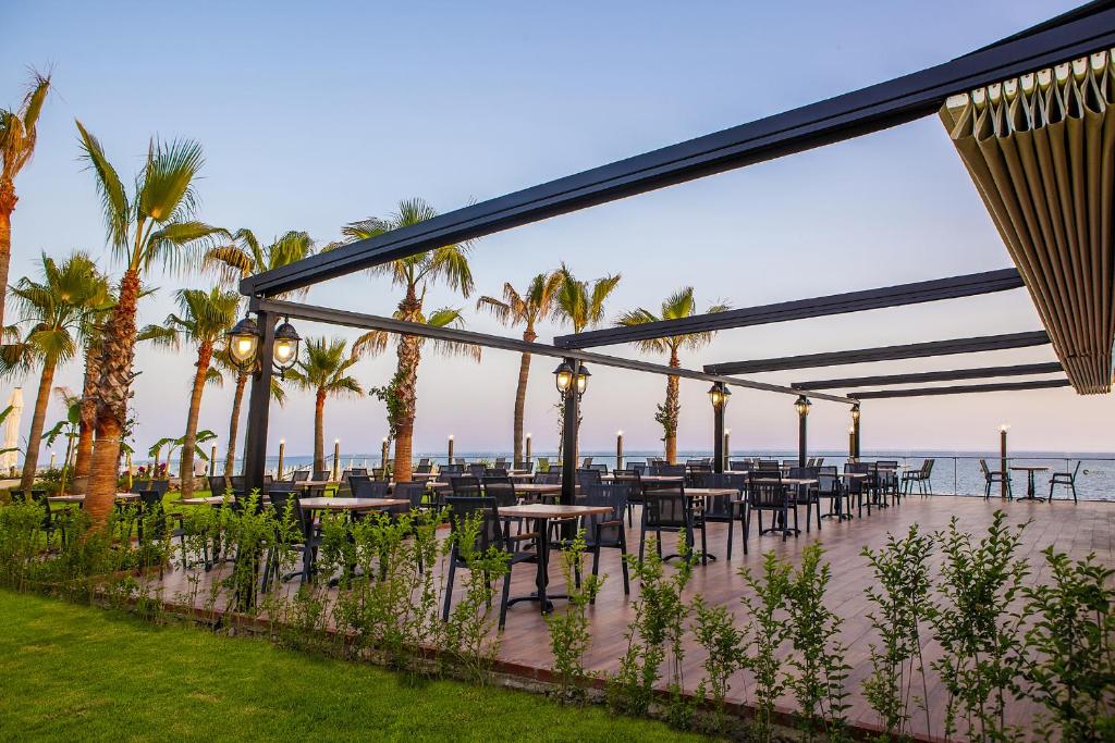 Āra restorāns Aria Resort & Spa Hotel piekrastē ar palmām un skatu uz jūru