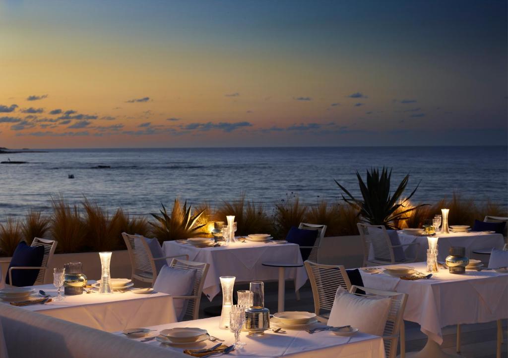 Romantisks vakariņu galds I-Resort Beach Hotel & Spa piekrastē saulrieta gaismā.