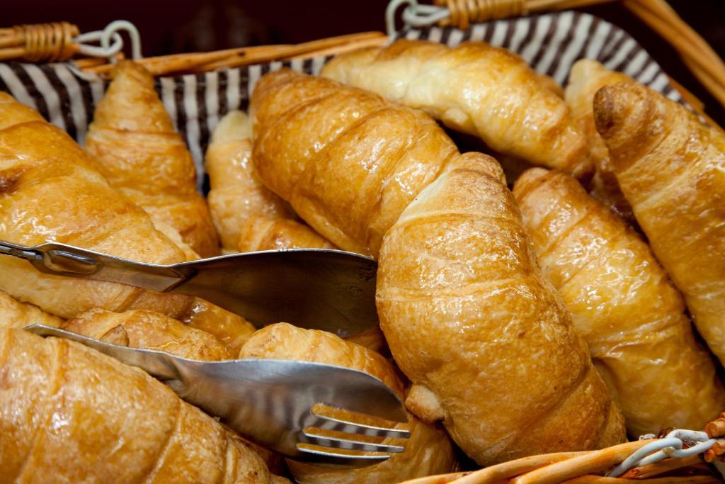 Kruasāni sakrauti grozā ar metāla tējkarotēm, izceļot to zeltainās krāsas un kraukšķīgumu. Ideāla izvēle brokastīm vai uzkodām.