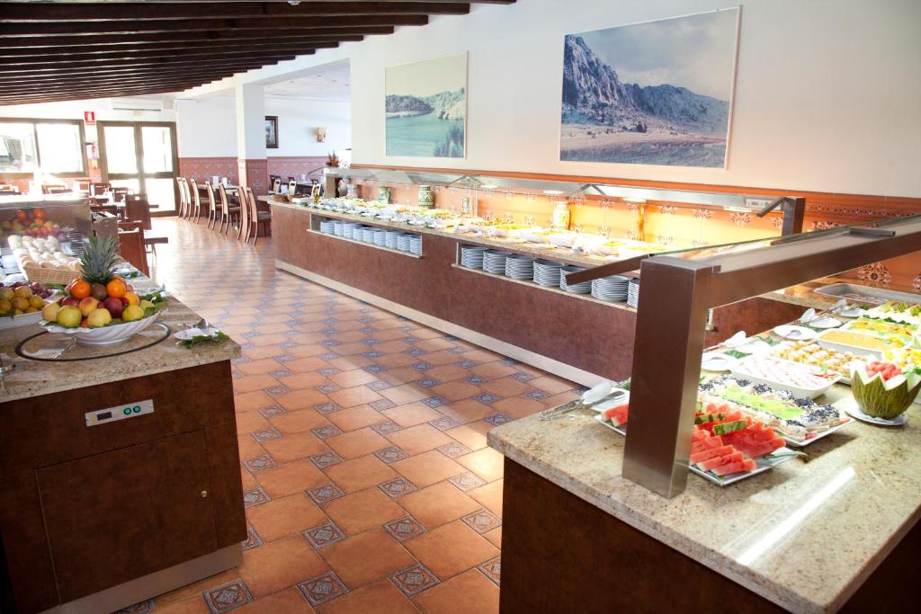 Lielas ēdienu bufetes skats ar augļu un salātu izvēli restorānā. Telpa ir gaiša un viesmīlīga, piedāvājot dažādas ēdienu iespējas.