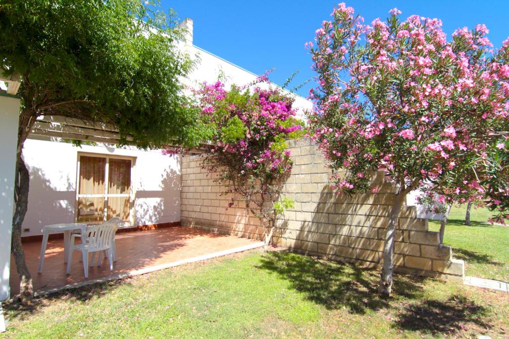 Mierīga terase ar galdu un krēslu, apkārt krāšņi ziedošas krūmu grupas. Ideāla vieta atpūtai dabā.