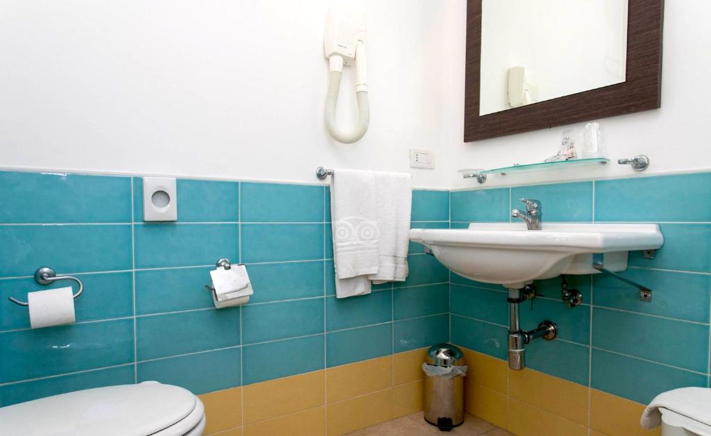 Mūsdienīgs vannas istabas interjers ar zilām un dzeltenām flīzēm, baltu izlietni un spoguli, kā arī nepieciešamajām sanitārajām iekārtām.