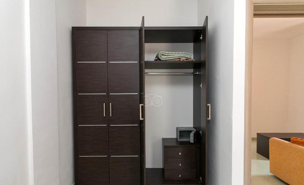 Melna skapja interjers ar atvērtu plauktu un nelielu mikroviļņu krāsni apakšā, blakus ir ērtas mēbeles.