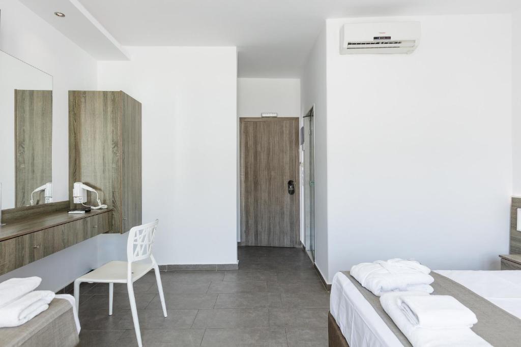 Moderns numurs ar koka mēbelēm, spoguli un gaismas avotiem, kas rada mierīgu atmosfēru. Redzama gulta un krēsls, kā arī durvis uz vannas istabu.