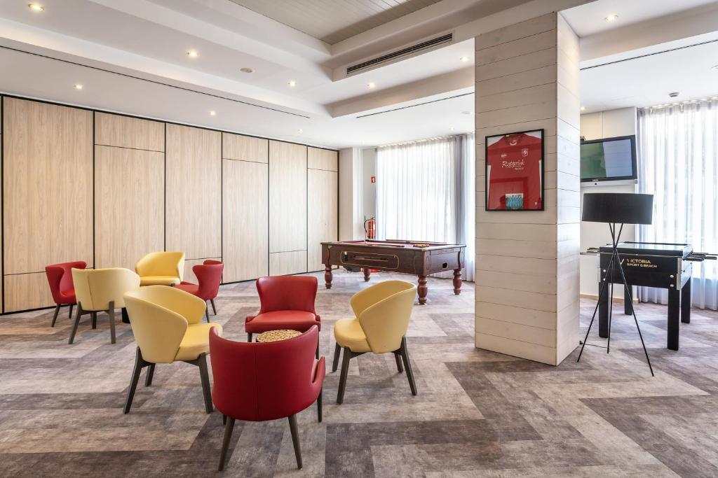 AP Victoria Sport & Beach Hotel atpūtas zona ar biljarda galdu, galda futbolu un ērtiem sarkanies un dzelteniem krēsliem.