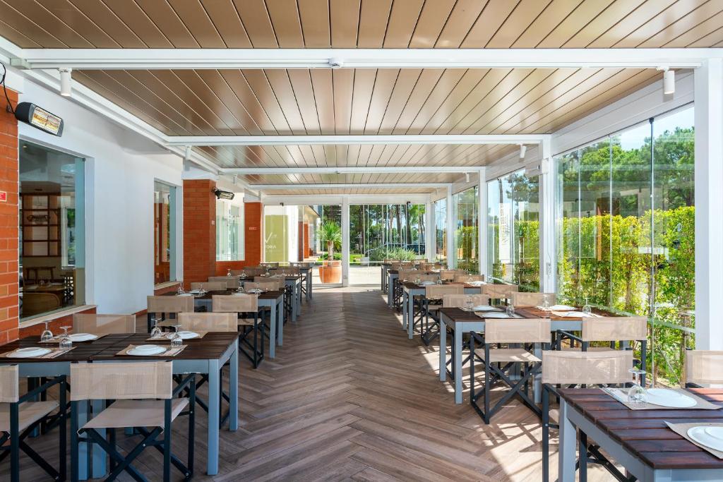 AP Victoria Sport & Beach Hotel plašā restorāna terase ar klātiem galdiem un stikla sienām.